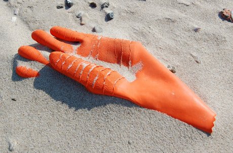 Orange gummihandske i sandet